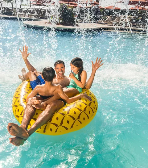 Dad and two kids on float under waterfall