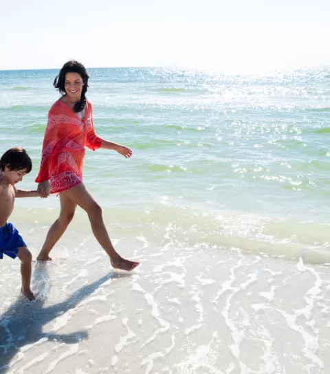 A woman walks on the beach with her young son in N