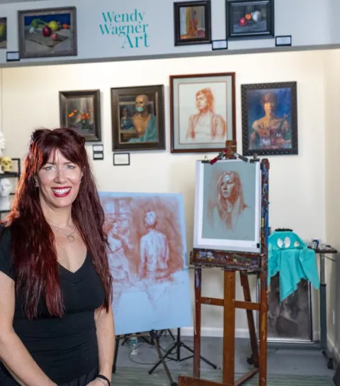 Female artist posing in gallery in front of her work