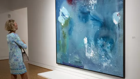 A woman looks at a piece of art in a gallery. A woman looks at a piece of art in a gallery.