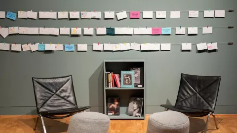 Art is displayed on a gallery wall. Art is displayed on a gallery wall.