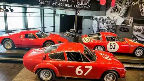 Three red vintage sports cars sit in a gallery. Three red vintage sports cars sit in a gallery.