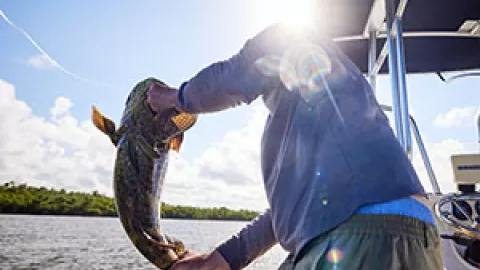 Man pulling in a fish from a boat