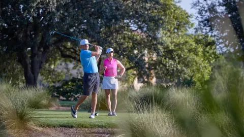 A man and a woman play golf.