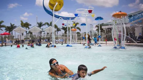 A woman and her son play in the pool at an aquatic