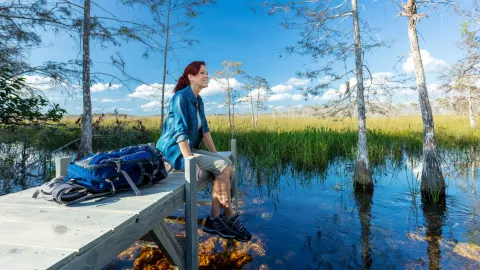 A woman sits on a dock during a hike in the Evergl