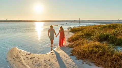 A couple holds hands at Tigertail Beach at sunset