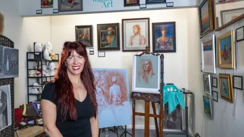 Female artist posing in gallery in front of her work