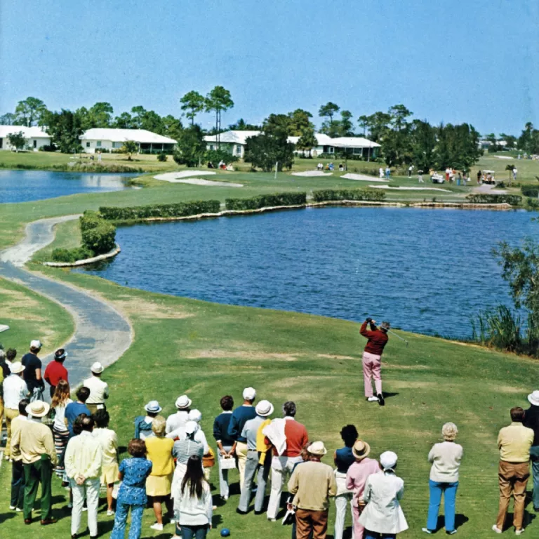 Golfers on the green looking towards a lake Photo