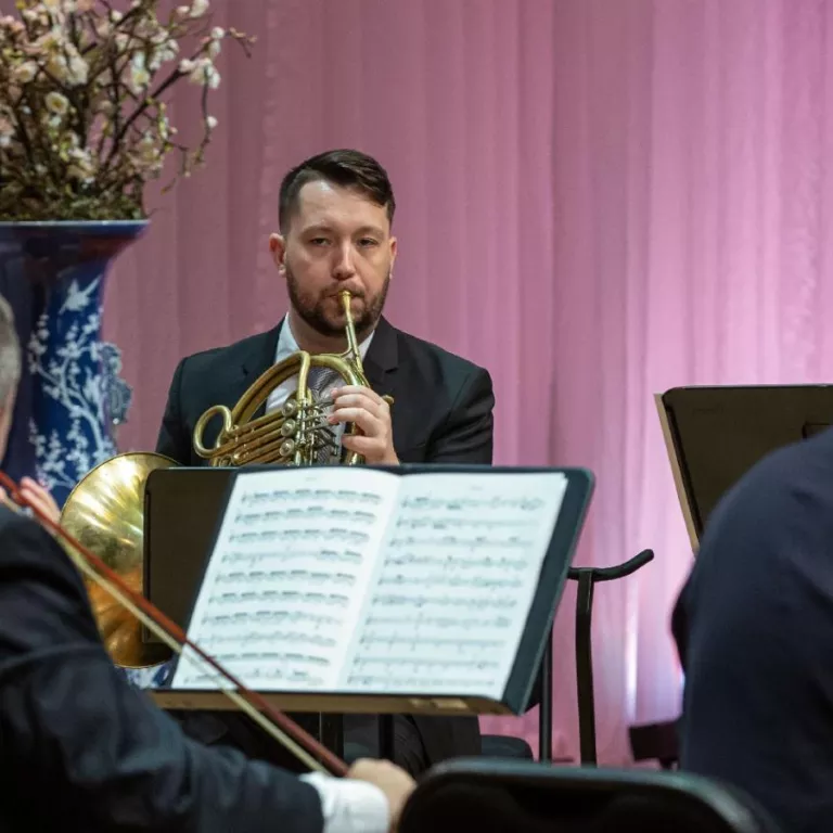 A member of the Naples Philharmonic plays the French horn during a performance. Photo