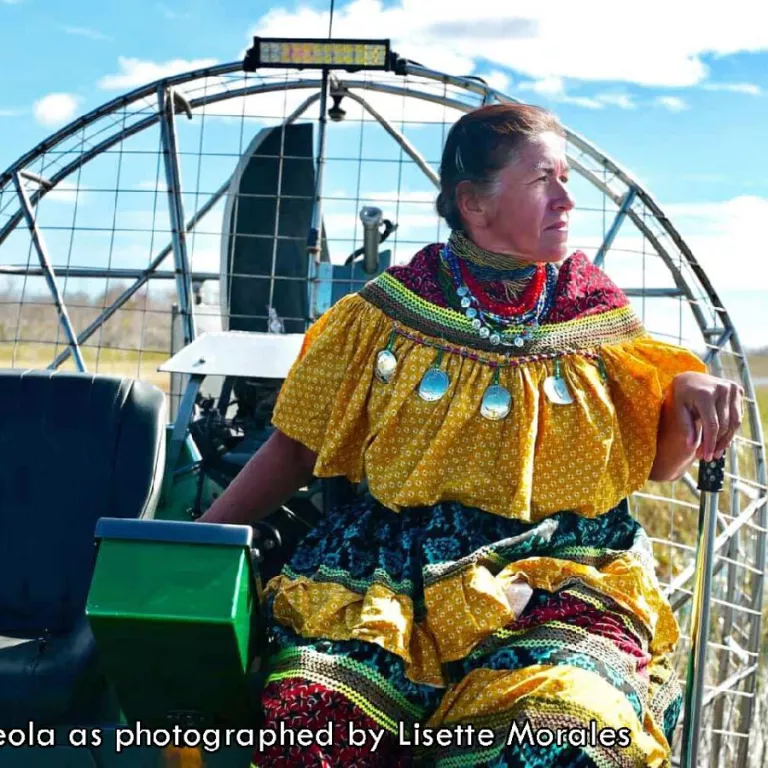 Betty Osceola on an airboat in traditional dress as photographed by Lisette Morales. Photo