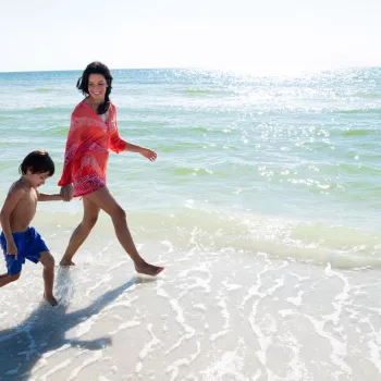 A woman walks on the beach with her young son in N