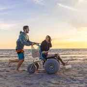 Man pushing woman in wheelchair on the Clam Pass Beach