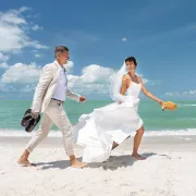 bride and groom running on the coast