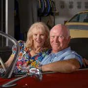 john and lisa sitting in a red porsche smiling