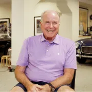 pat mullaney smiles in his garage with his car collection