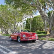 vintage red porsche drives down banyan tree lined road
