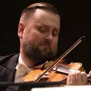 Image of Zachary DePue of the Naples Philharmonic on stage playing violin during a performance Photo