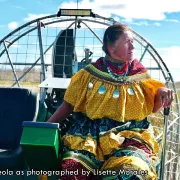 Betty Osceola on an airboat in traditional dress as photographed by Lisette Morales. Photo