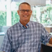 A man with tan skin, dark hair, and glasses wearing a blue plaid shirt Photo
