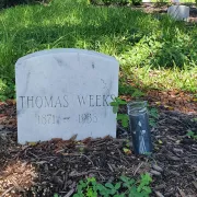 Gravestone on dirt and a tall black candle sporting a Grim Reaper graphic Photo