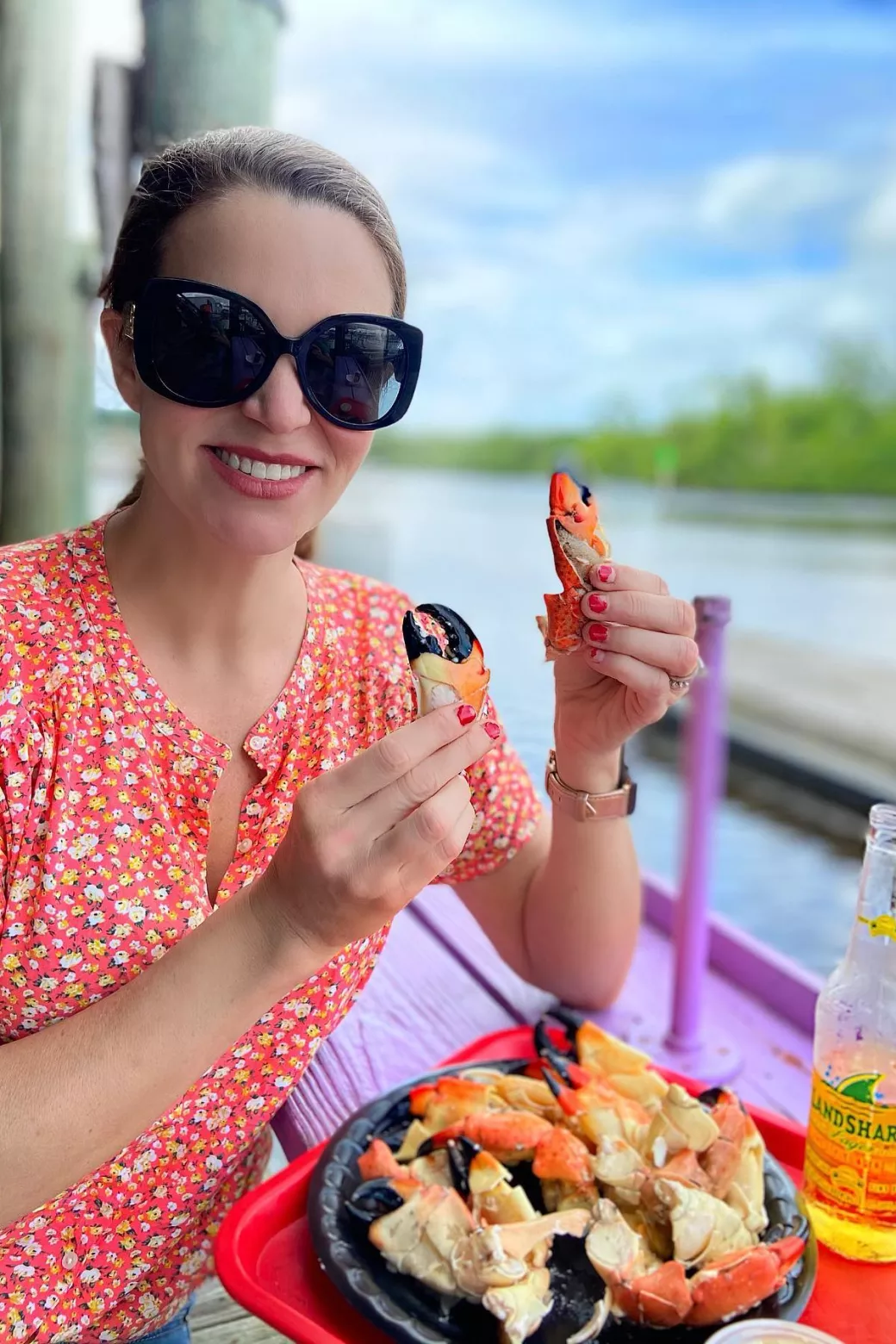 Woman holding stone crab claws with a full plate i