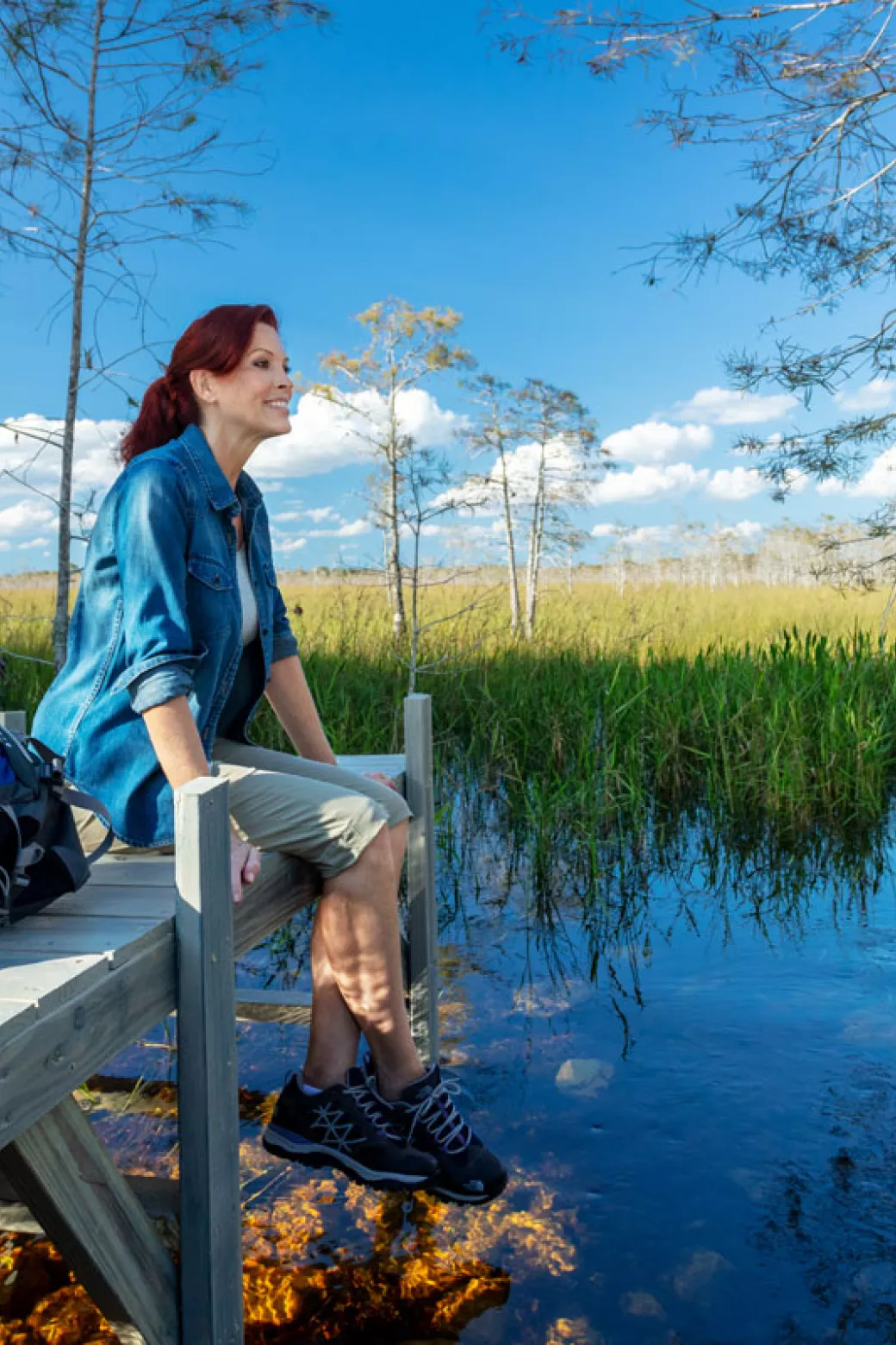 A woman sits on a dock during a hike in the Evergl