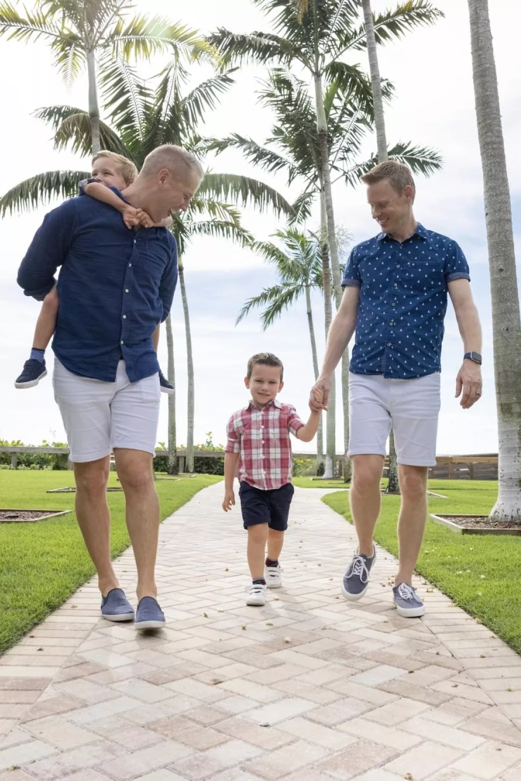 Two dads walk with their young sons in the park outside Naples Beach.