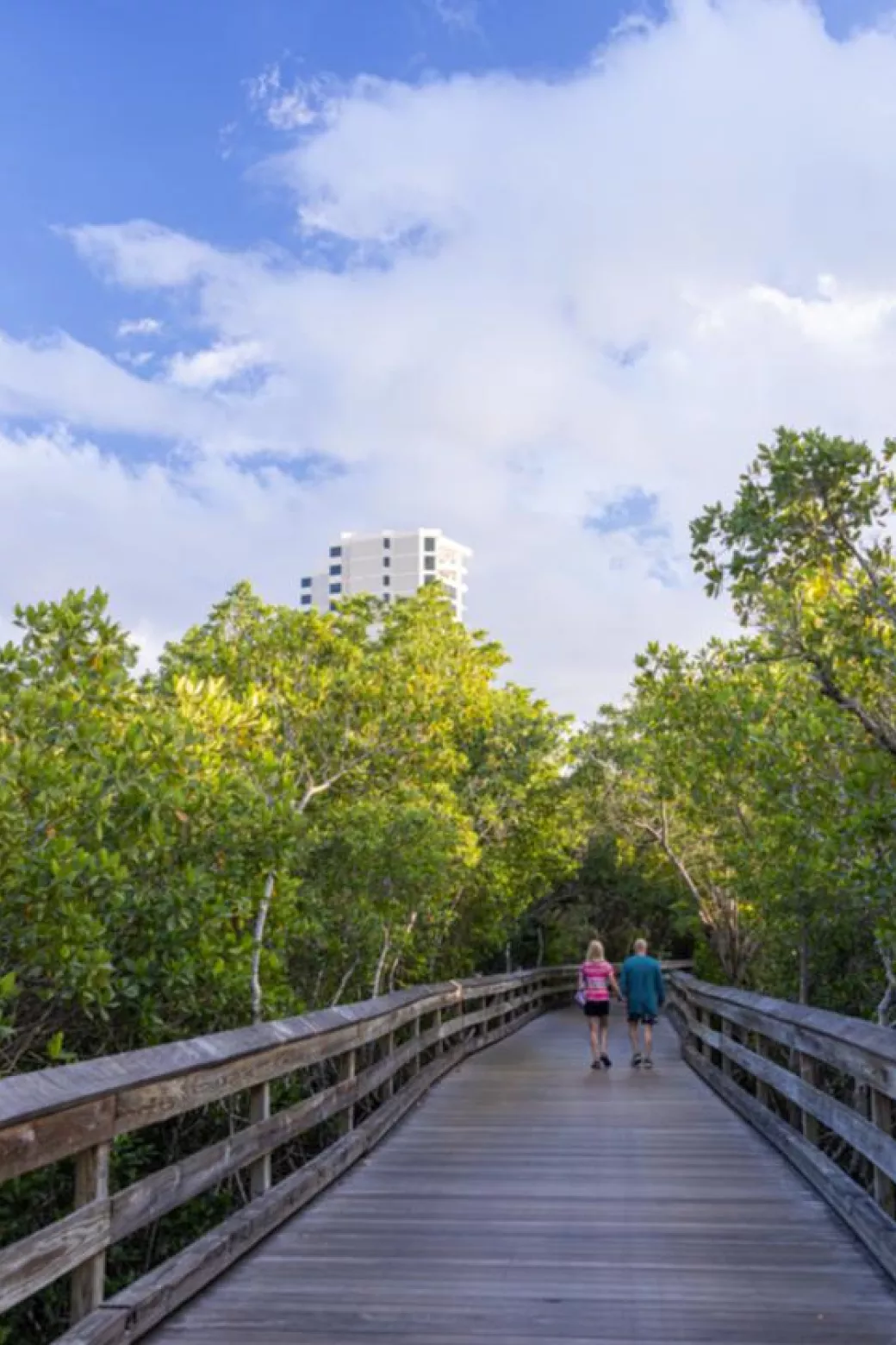 Couple walking down boardwalk at Clam Pass Park.