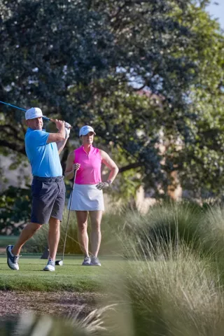 A man and a woman play golf.