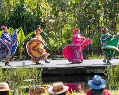 Four women in traditional Mexican dresses dance on