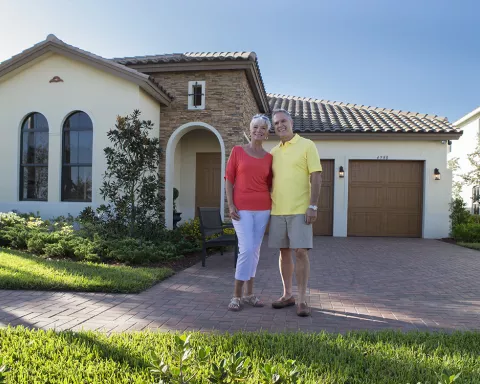 Couple standing in front of their Paradise Coast h Couple standing in front of their Paradise Coast h