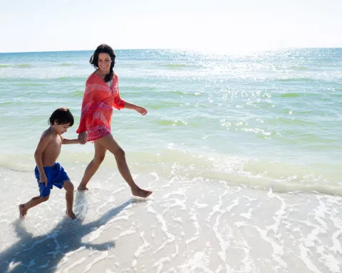 A woman walks on the beach with her young son in N