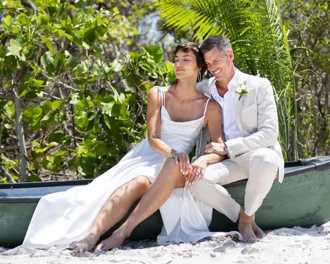 bride and groom sitting on canoe on sandy beach