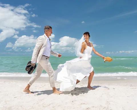 bride and groom running on the coast