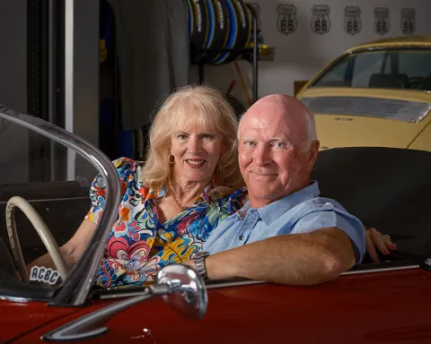 john and lisa sitting in a red porsche smiling