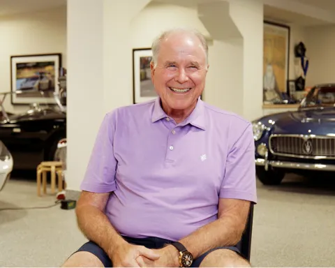 pat mullaney smiles in his garage with his car collection