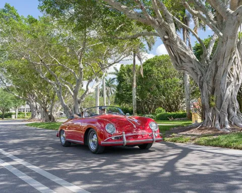 vintage red porsche drives down banyan tree lined road