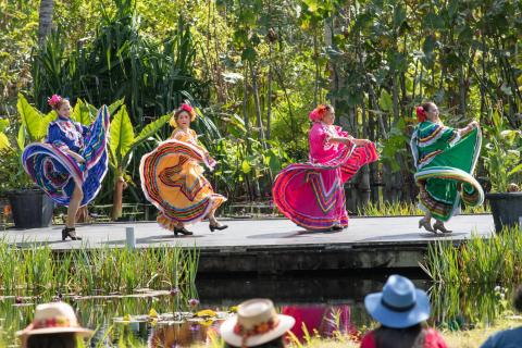 Four women in traditional Mexican dresses dance on