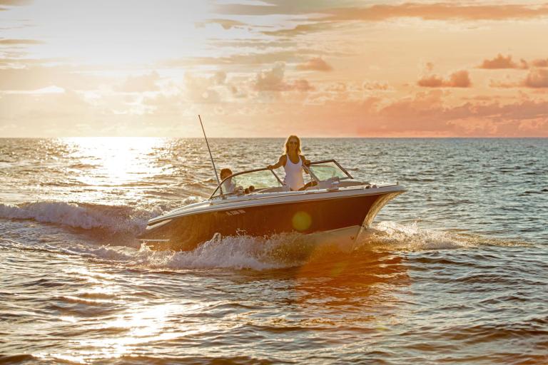 A couple rides a speedboat on the ocean at sunset. A couple rides a speedboat on the ocean at sunset.