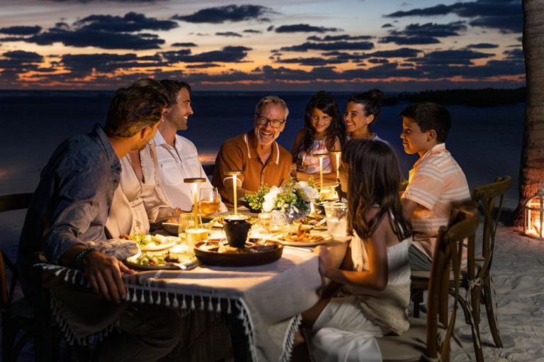 family dining on the beach at dusk