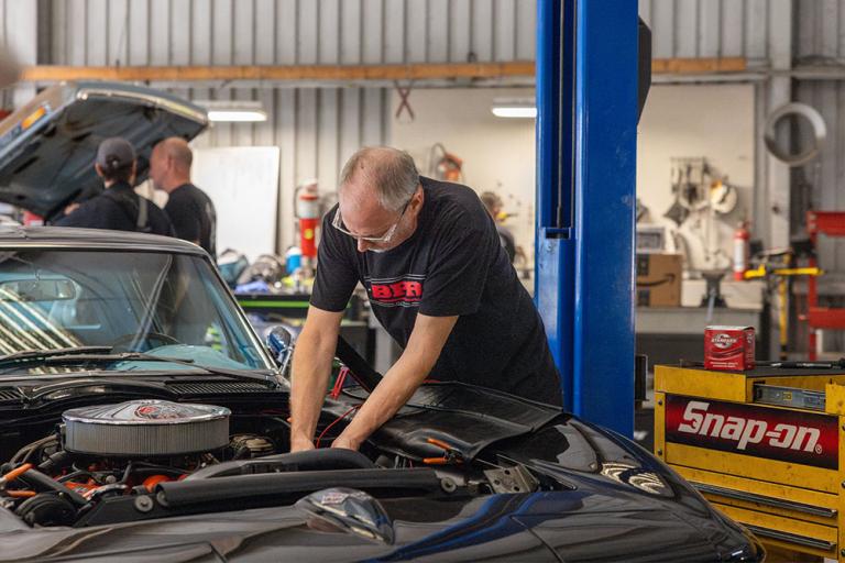 jeff bar works on a car in his shop